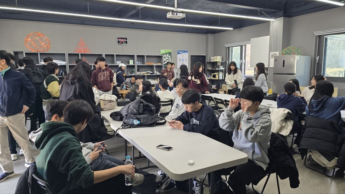 실내 책상에 둘러앉아 포디프레임 부품을 잇는 학생들