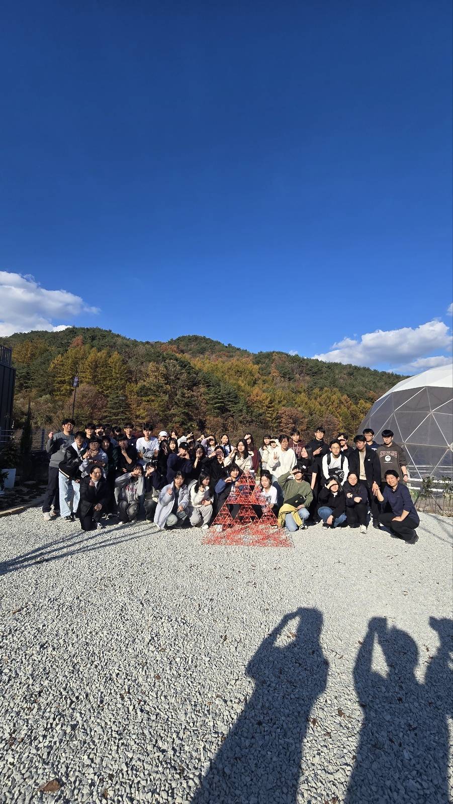 자갈 마당에서 산을 배경으로 찍은 단체 사진